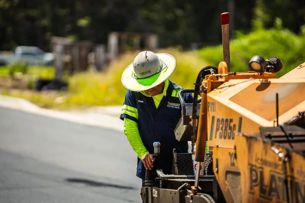 A worker operates Platinum Paving's asphalt paving machine.