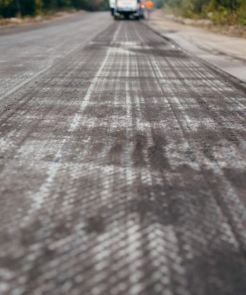Road milling machine removes asphalt from old road and loads milled asphalt in dump truck.