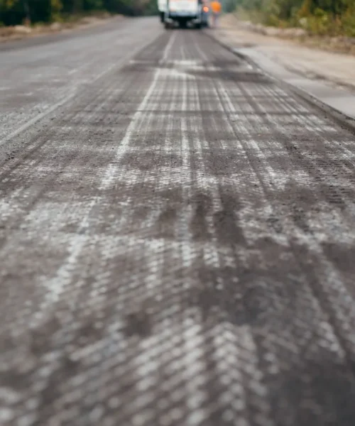 Road milling machine removes asphalt from old road and loads milled asphalt in dump truck.