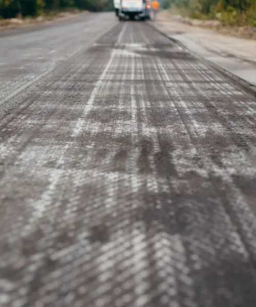 Road milling machine removes asphalt from old road and loads milled asphalt in dump truck.