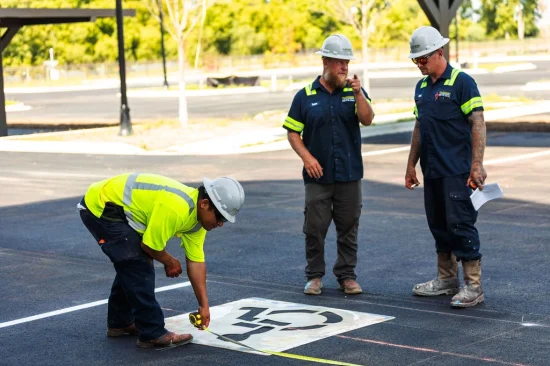 Contractor painting new ADA signs on a parking space.