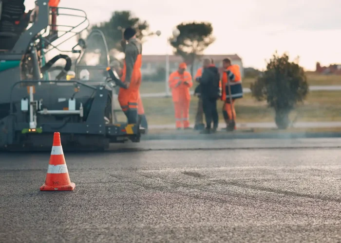 Workers use an asphalt paving machine.