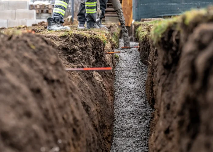 Workers lay new concrete in a drainage ditch.