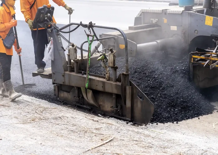 A machine pours hot asphalt onto the road.