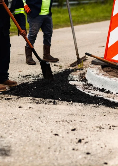 Platinum Paving workers fill a pothole with asphalt.