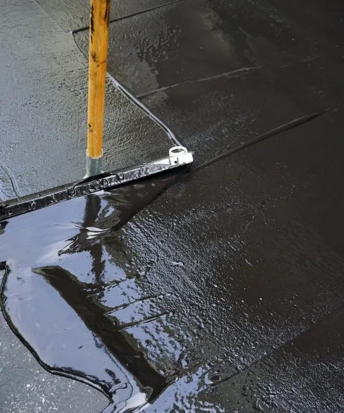 Man sealing asphalt driveway/Sealcoating selective focus